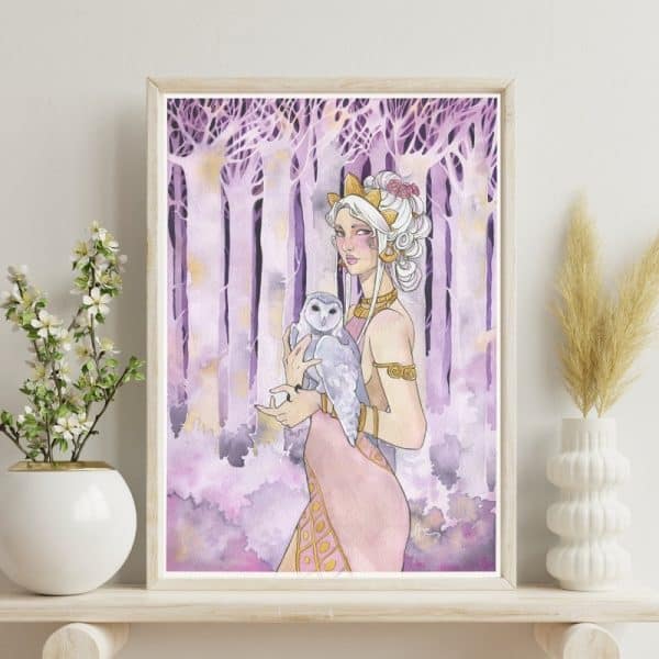 Une aquarelle aux tons violets encadrée, posée sur une tablette en bois clair, â côté d'une plante en pot. L'aquarelle représente une fée devant une forêt couleur améthyste.