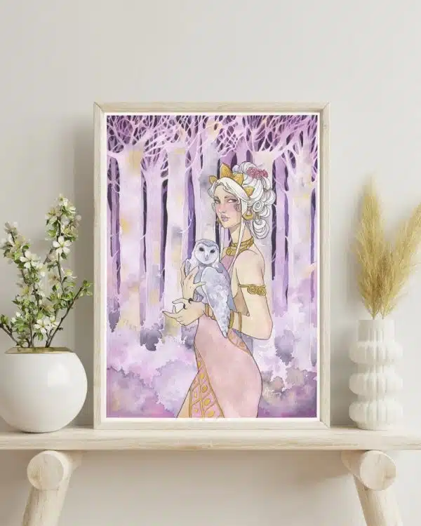 Une aquarelle aux tons violets encadrée, posée sur une tablette en bois clair, â côté d'une plante en pot. L'aquarelle représente une fée devant une forêt couleur améthyste.