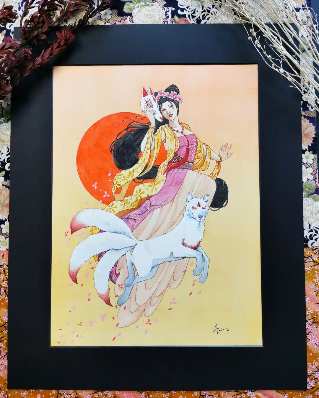 Une femme aux longs cheveux noirs flotte dans les airs devant un soleil rouge orangé. Un renard blanc marqué de rouge l'accompagne. La dame au renard blanc est une aquarelle originale issue de la collection Esprits japonais par Aemarielle. Elle incarne le kitsune.