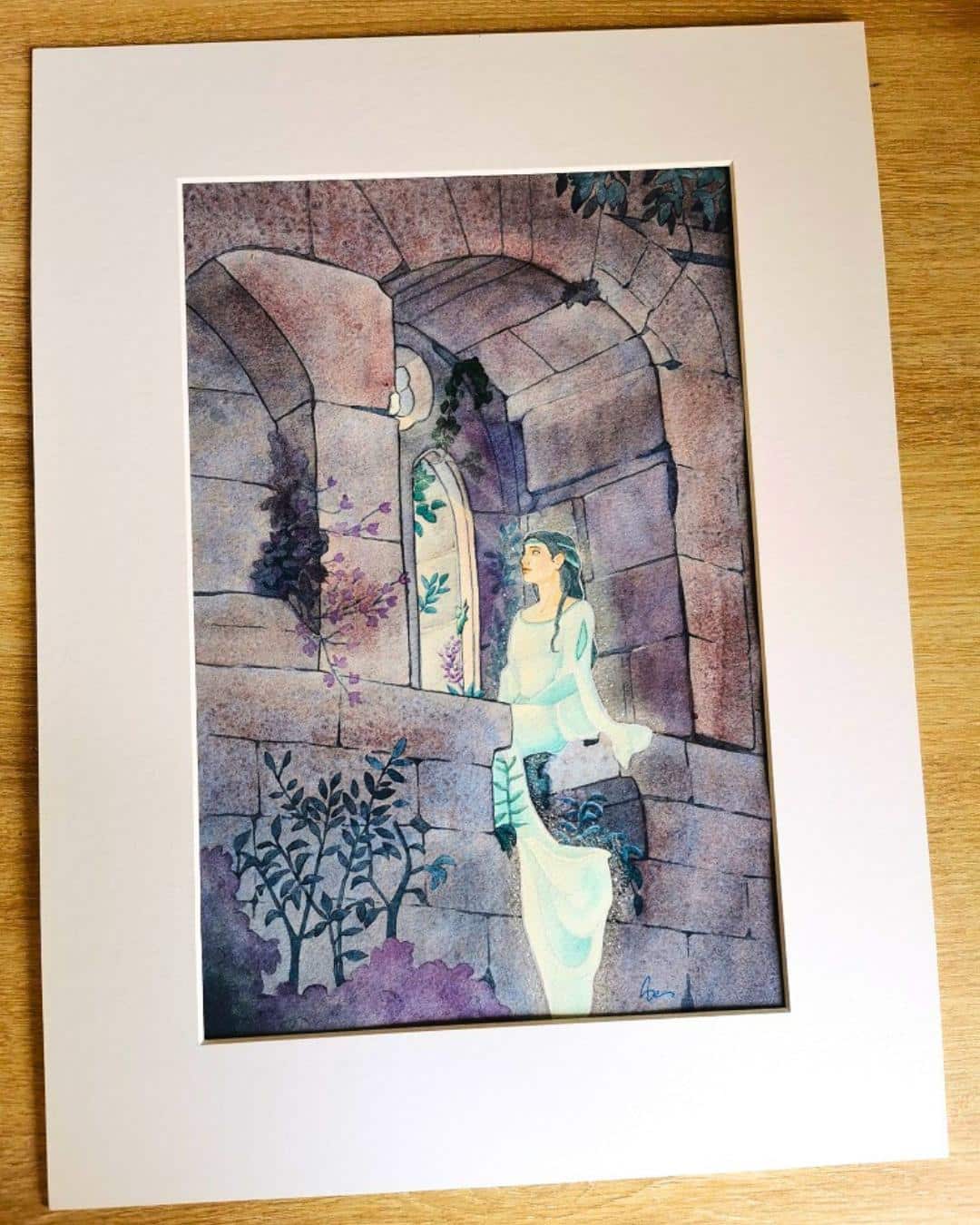 Une aquarelle dans un passepartout en carton blanc représentant une femme assise à la fenêtre d'un château en ruine, de nuit. La dame du Wasenbourg par Aemarielle