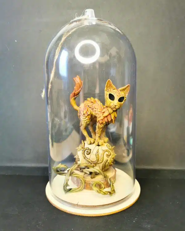 Un nekodama, esprit chat des bois en résine sous une cloche décorative transparente.