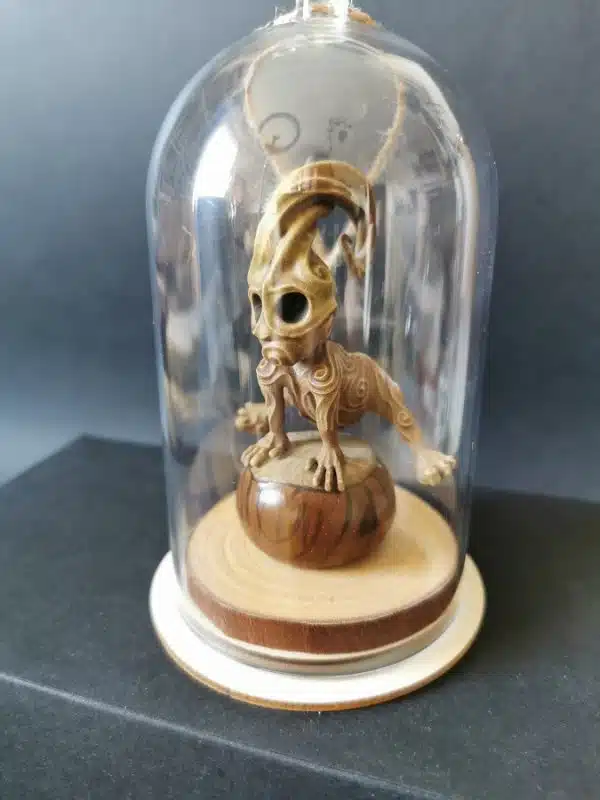 Un kodama en résine sous cloche transparente, qui saute par dessus un marron.
