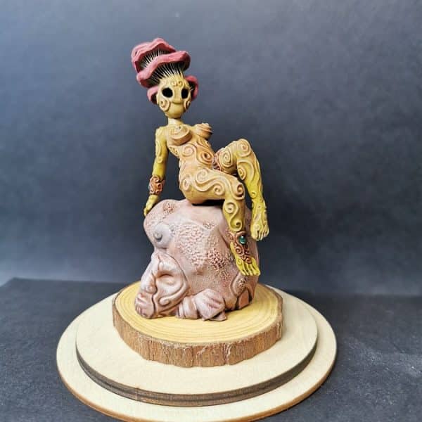 Un kodama féminin assis sur un rocher qui ressemble à du grès rose.