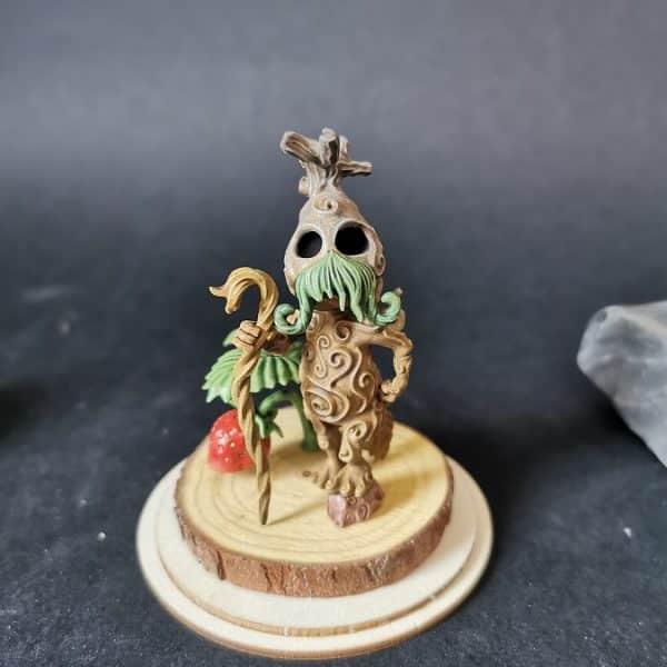 un kodama gardien de fraise en résine sur un socle en bois