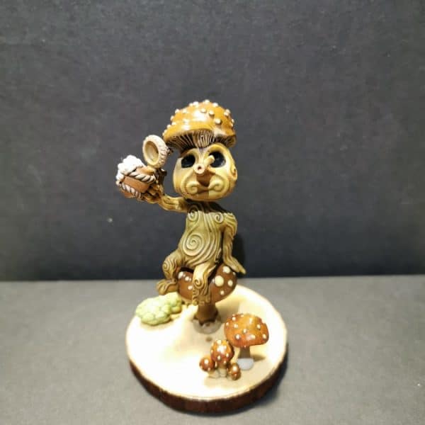 Un kodama coiffé d'une cosse de marron, en train de lever sa chope à ta santé.