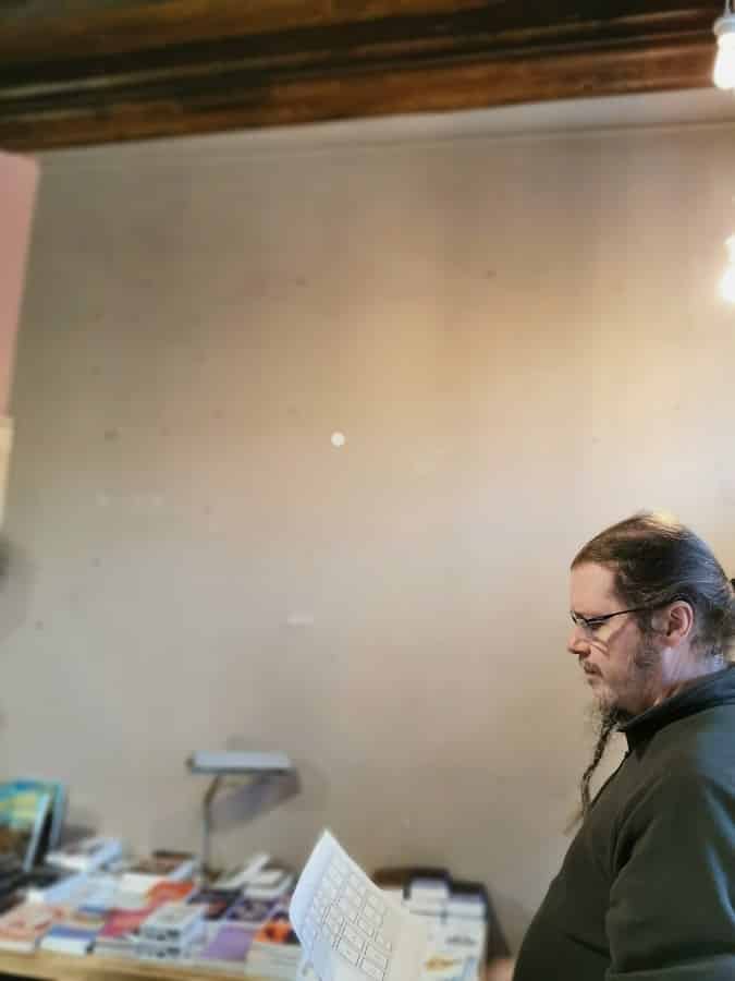 Un grand mur gris vide devant lequel Steph étudie le plan de l'accrochage des aquarelles.