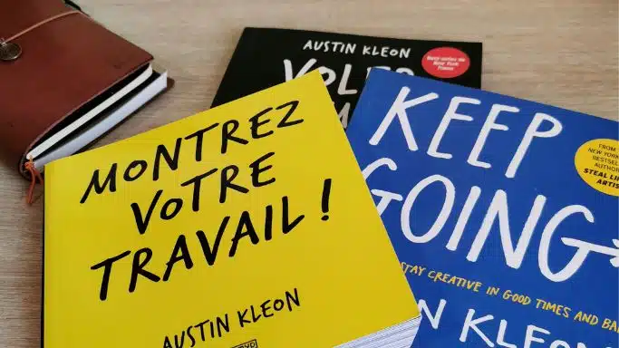 Les 3 livres d'Austin Kleon - Montrer votre travail, volez comme un artiste et Keep going, empilés à côté d'un carnet de notes.