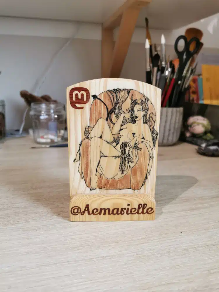 Un totem en bois gravé d'une diablesse sexy et du logo Mastodon, avec la mention de mon nom d'utilisatrice Mastodon