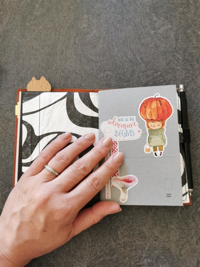 Une couverture en cuir ouverte sur un carnet de notes et une pochette pour ranger des papiers et stickers. Mon carnet de vacances d'été.