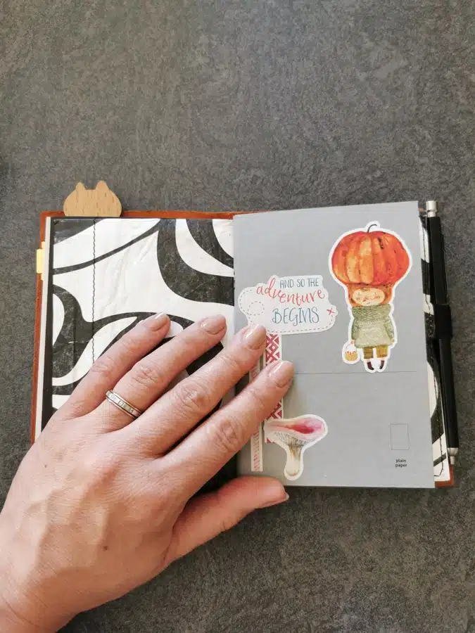 Une couverture en cuir ouverte sur un carnet de notes et une pochette pour ranger des papiers et stickers. Mon carnet de vacances d'été.